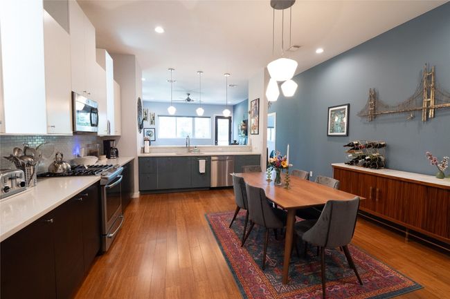 Kitchen with appliances with stainless steel finishes, light countertops, white cabinets, pendant lighting, and tasteful backsplash | Image 25