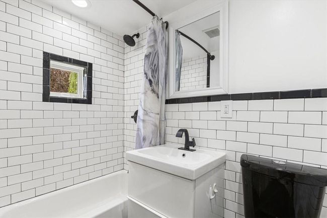 Bathroom featuring vanity, shower / tub combo, and tile walls | Image 8