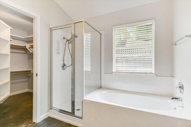 Primary Bathroom featuring a deep soaking garden bathtub, stained concrete floors, a walk in closet, and a stall shower | Image 11