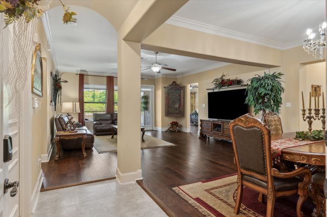 Dining area featuring ceiling fan, crown molding, wood finished floors, baseboards, and a chandelier | Image 4