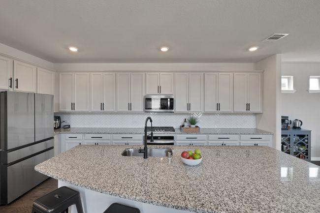 Kitchen featuring a sink, light stone countertops, a kitchen breakfast bar, appliances with stainless steel finishes, and visible vents | Image 13