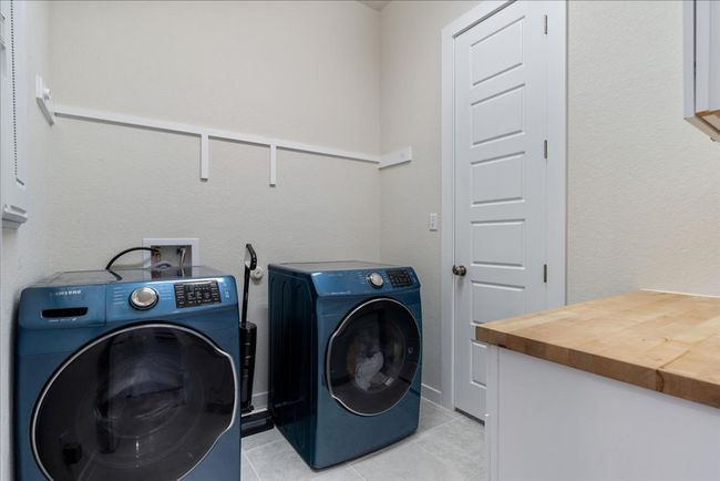Laundry room featuring laundry area, light tile patterned floors, and washing machine and clothes dryer | Image 38