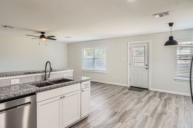 Kitchen with a sink, visible vents, white cabinetry, stone counters, and stainless steel dishwasher | Image 6