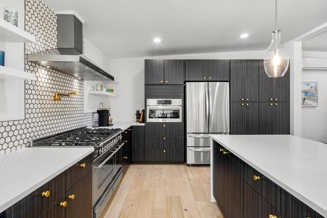 Kitchen with open shelves, wall chimney exhaust hood, light countertops, light wood-type flooring, and stainless steel appliances | Image 10
