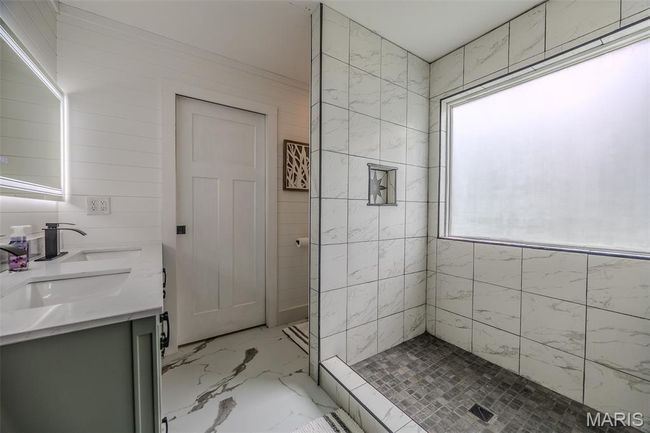 Full bathroom with double vanity, marble finish floors, and tiled shower | Image 30