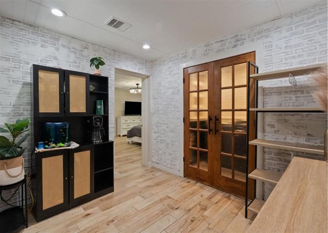 Stylish home office/flex space with whitewashed brick walls, French doors, and wood-look floors for a cozy yet professional vibe. | Image 24
