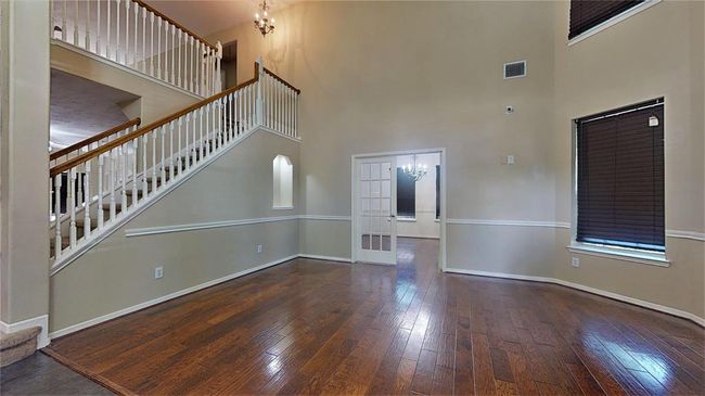 Discover a spacious living room featuring elegant hardwood floors, abundant natural light, and a stunning high ceiling, perfect for entertaining or relaxing. | Image 4