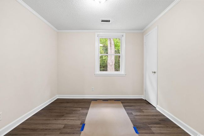 Empty room featuring a textured ceiling, wood finished floors, baseboards, and ornamental molding | Image 34