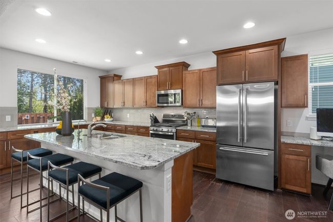 The expansive center island offers ample prep space, seating for four, and an under-mount sink including a filtered alkaline drinking water faucet - perfect for hosting guests or enjoying casual meals. | Image 10