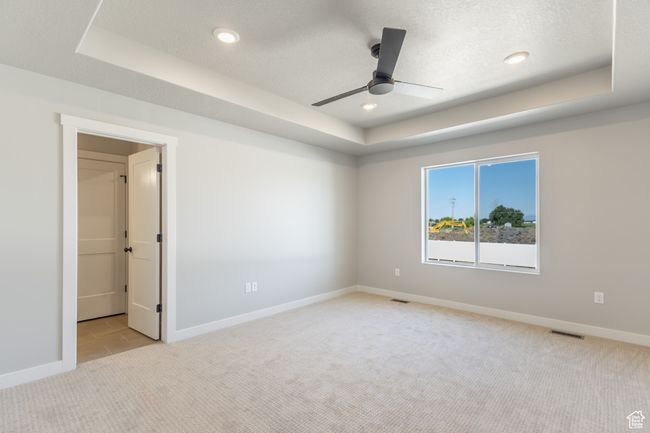 Empty room featuring a raised ceiling, light colored carpet, a ceiling fan, and recessed lighting | Image 16