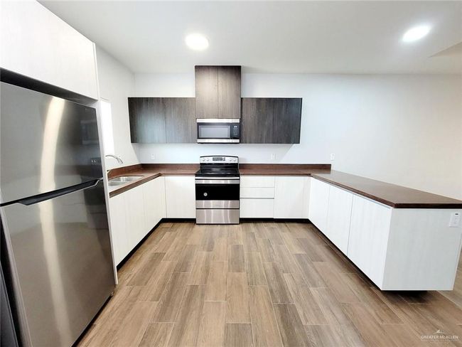 Kitchen with a sink, modern cabinets, dark countertops, and stainless steel appliances | Image 4
