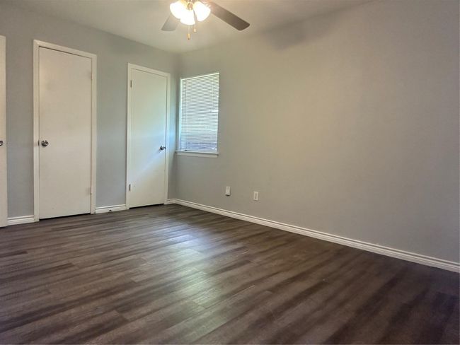 Unfurnished bedroom with dark wood-type flooring, baseboards, and a ceiling fan | Image 14