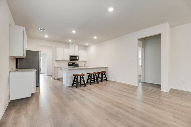 Kitchen featuring stainless steel appliances, a kitchen breakfast bar, light wood-style floors, white cabinets, and baseboards | Image 14
