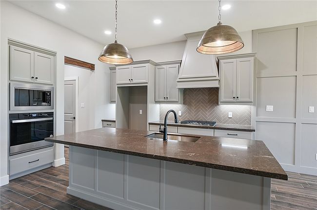 Kitchen with stainless steel appliances, a sink, custom exhaust hood, decorative backsplash, and dark wood-style floors | Image 12