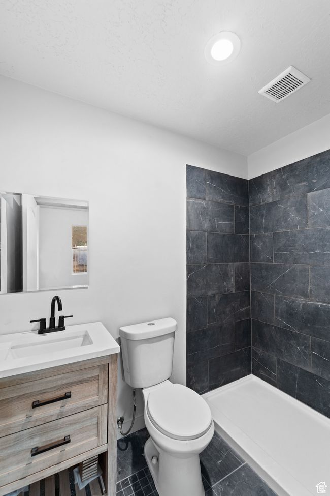 Bathroom with tile patterned floors, a tile shower, toilet, vanity, and visible vents | Image 12