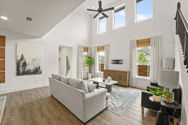 Living room with stairway, ceiling fan, a towering ceiling, recessed lighting, and wood finished floors | Image 13