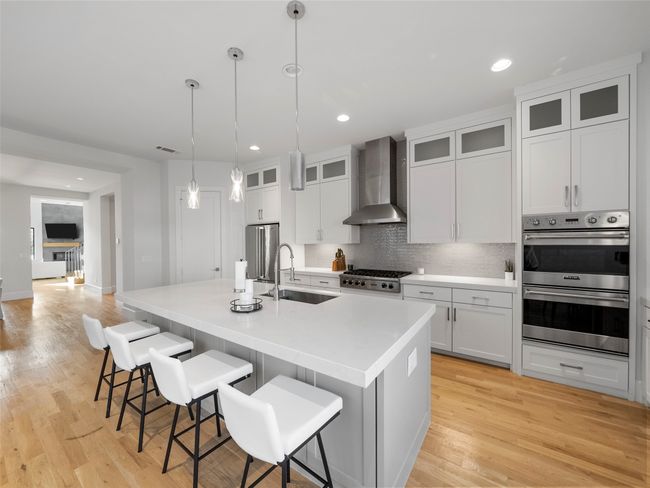 Kitchen with wall chimney range hood, stainless steel appliances, light wood-style flooring, and recessed lighting | Image 13