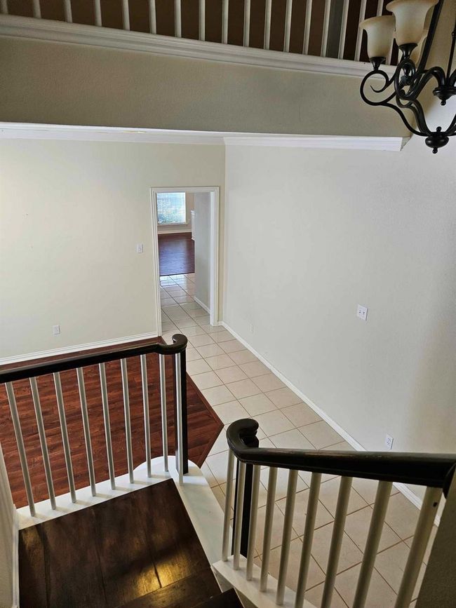 Stairway with crown molding, tile patterned flooring, and a chandelier | Image 8