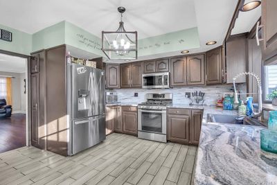 Kitchen featuring sink, hanging light fixtures, light hardwood / wood-style floors, light stone counters, and stainless steel appliances | Image 2