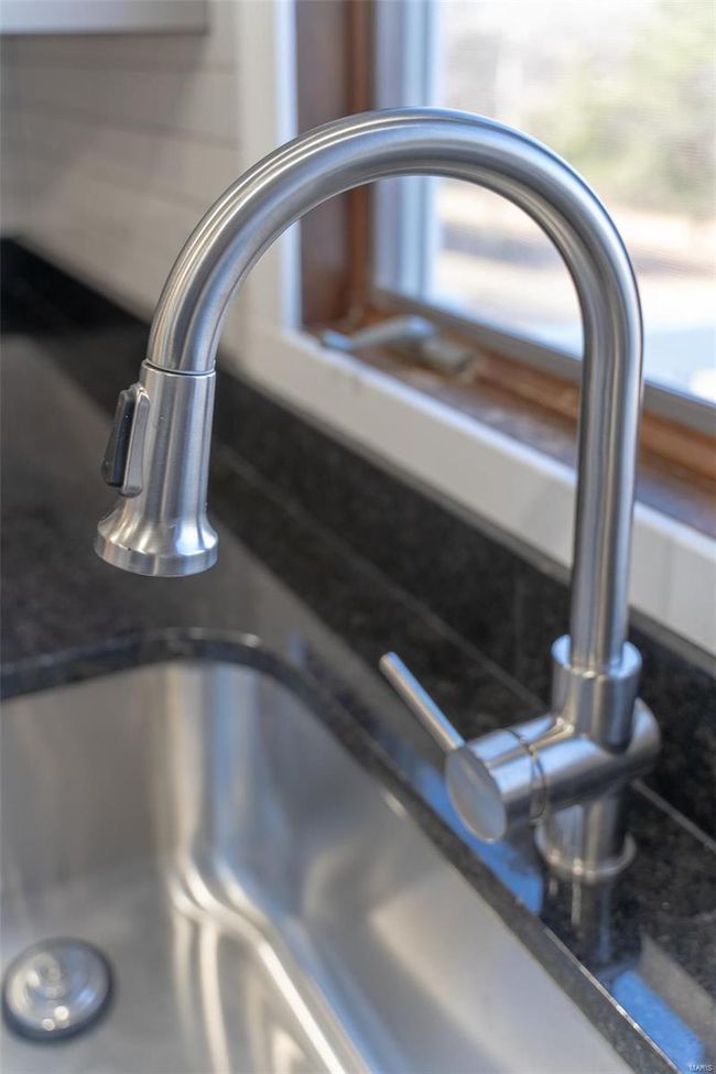 Room details with dark stone countertops and sink | Image 51