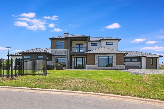 View of front of home with a standing seam roof, a metal roof, balcony, chimney, and brick and wood siding | Image 8