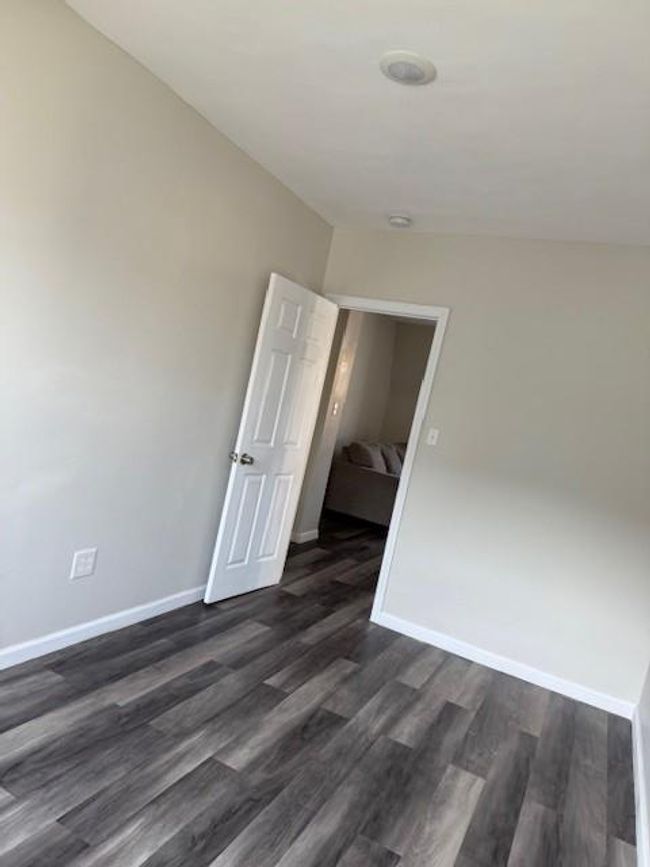 Empty room featuring dark wood-style flooring and a smoke detector | Image 15