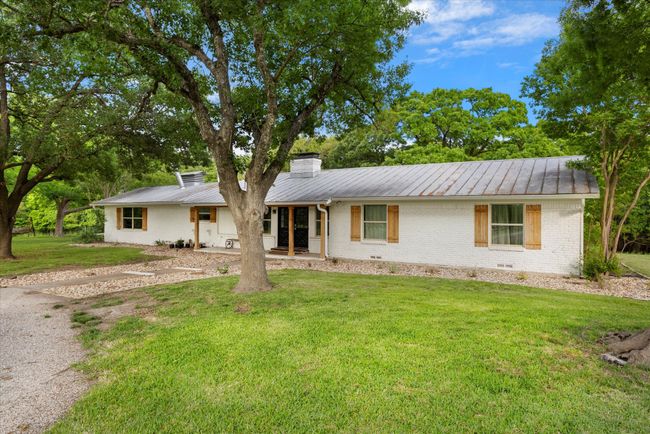 Ranch-style house featuring brick siding, metal roof, a front yard, and a standing seam roof | Image 4