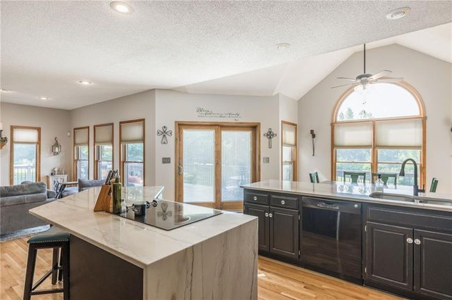 Kitchen with light wood finished floors, a sink, open floor plan, a kitchen island, and black appliances | Image 27