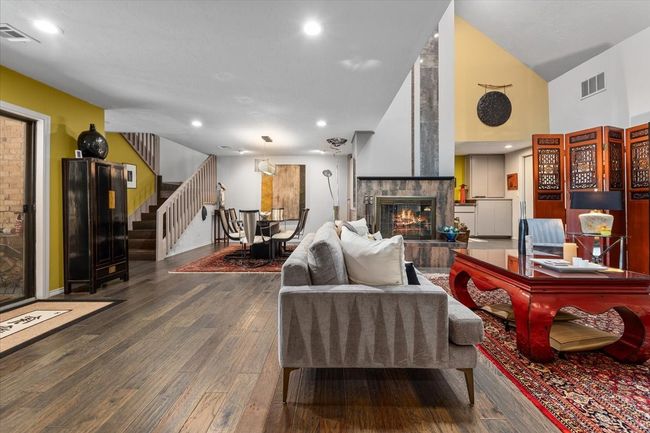 Living room with a custom fireplace facade, recessed lighting, stairs, and wood finished floors, vaulted ceilings. | Image 14