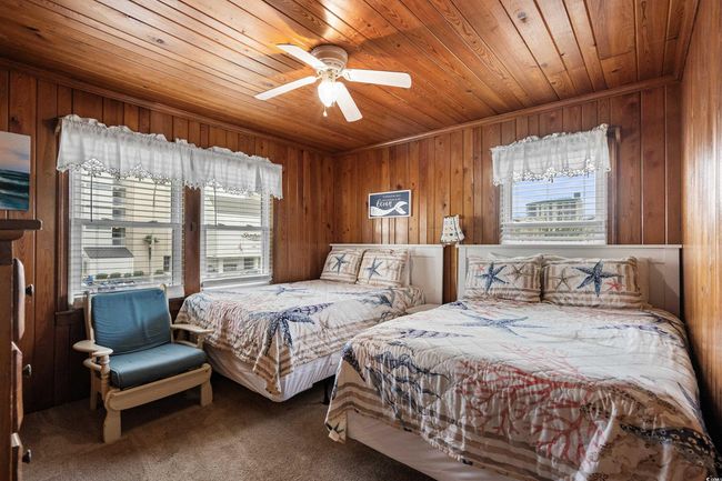 Bedroom featuring multiple windows, wooden ceiling, wooden walls, carpet floors, and a ceiling fan | Image 25