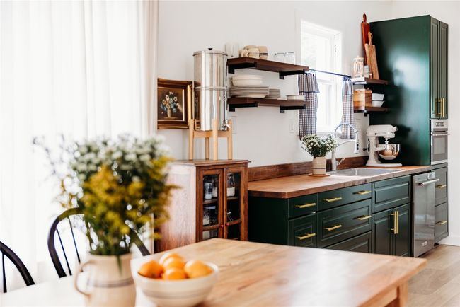 Kitchen with open shelves, butcher block countertops, green cabinets, light wood-style floors, and stainless steel dishwasher | Image 8