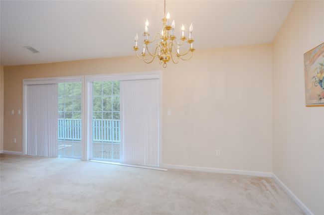 Carpeted empty room with a chandelier and baseboards | Image 8