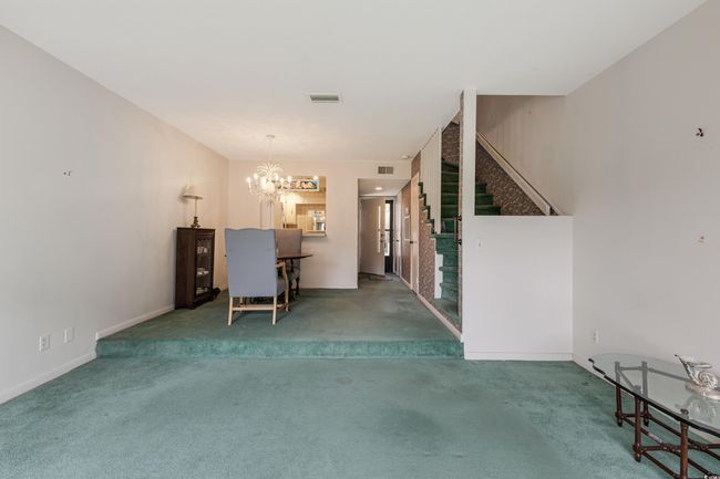 Unfurnished living room with a notable chandelier, carpet, stairway, and visible vents | Image 13