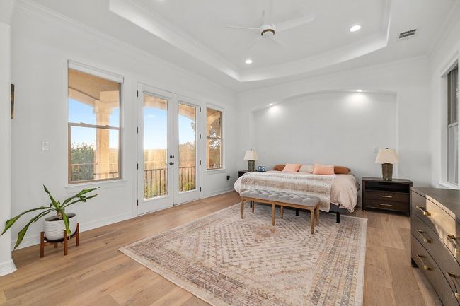 Bedroom with access to exterior, french doors, light wood-style flooring, a raised ceiling, and crown molding | Image 13