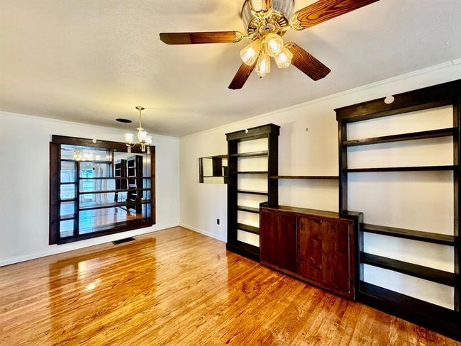 Spare room with wood finished floors, a chandelier, ornamental molding, and a ceiling fan | Image 5