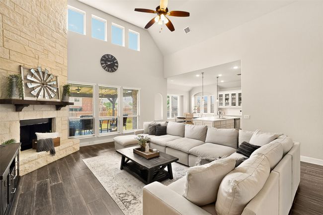 Living area featuring a ceiling fan, dark wood-type flooring, a fireplace, high vaulted ceiling, and baseboards | Image 7