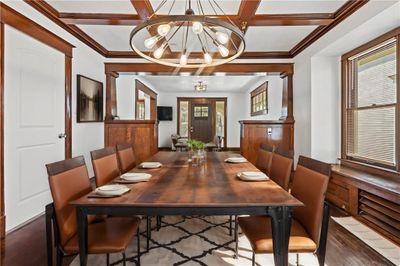 Dining area with a notable chandelier, wood-type flooring, coffered ceiling, and a healthy amount of sunlight | Image 2