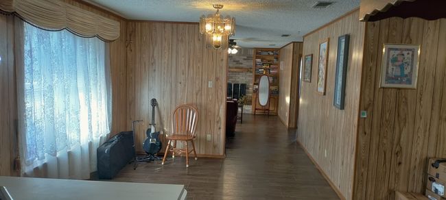 Hall featuring a chandelier, a textured ceiling, and wooden walls | Image 16