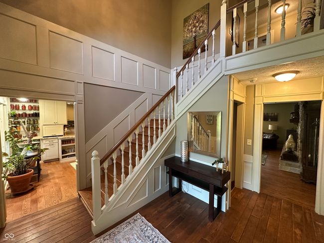 staircase featuring a decorative wall, hardwood / wood-style flooring, and a towering ceiling | Image 17