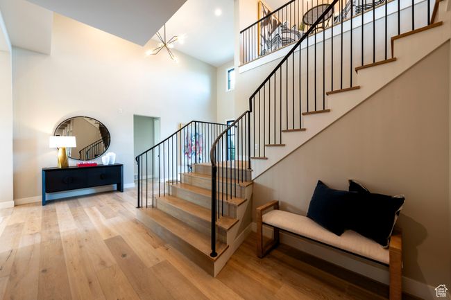 Staircase with a towering ceiling, a chandelier, and wood finished floors | Image 38