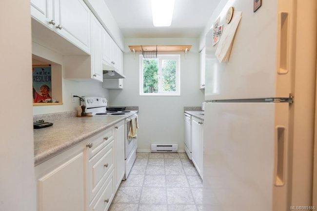 Kitchen featuring white appliances, white cabinets, and a baseboard heating unit | Image 7