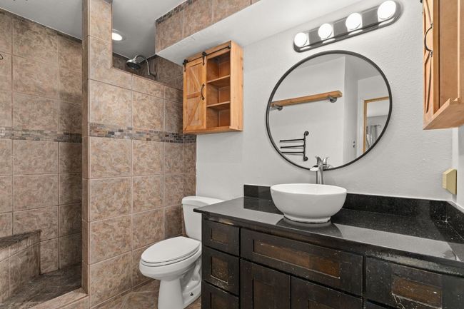 Primary bathroom with wood vanity and industrial accents | Image 17