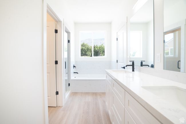 Bathroom featuring a garden tub, wood finished floors, double vanity, and a stall shower | Image 16