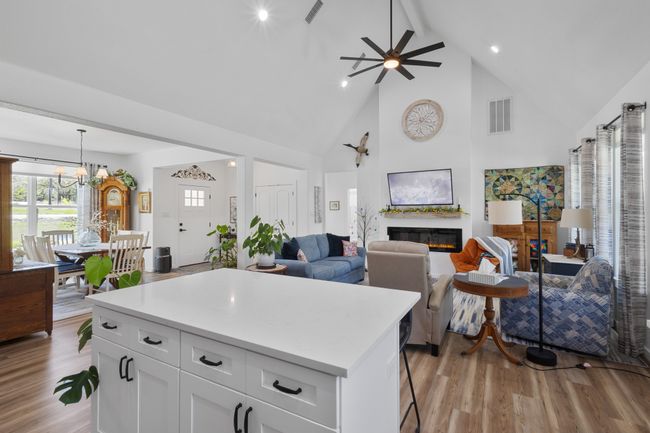 Kitchen featuring open floor plan, visible vents, ceiling fan with notable chandelier, and light wood-style flooring | Image 10