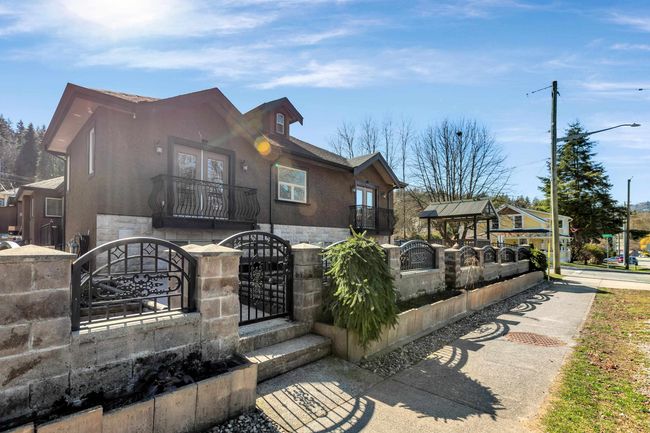 View of front facade with stone siding, a gate, a fenced front yard, and stucco siding | Image 6
