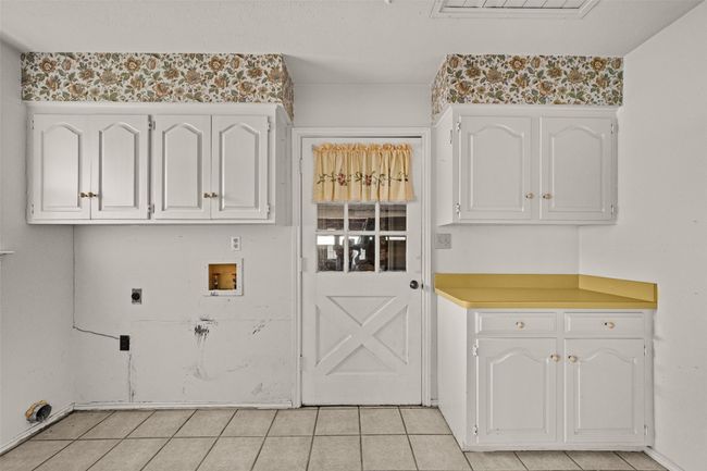 Washroom with light tile patterned flooring, hookup for an electric dryer, cabinet space, and hookup for a washing machine | Image 21