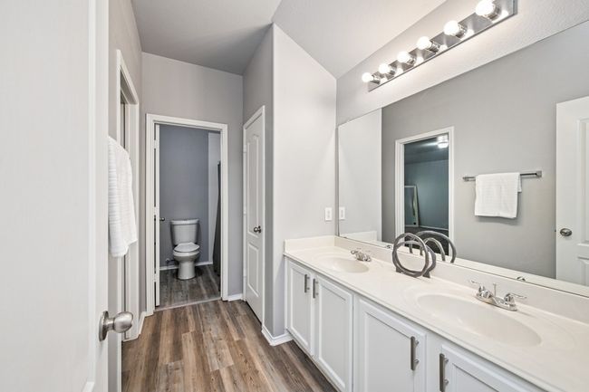 Full bathroom with a sink, toilet, double vanity, and wood finished floors | Image 30