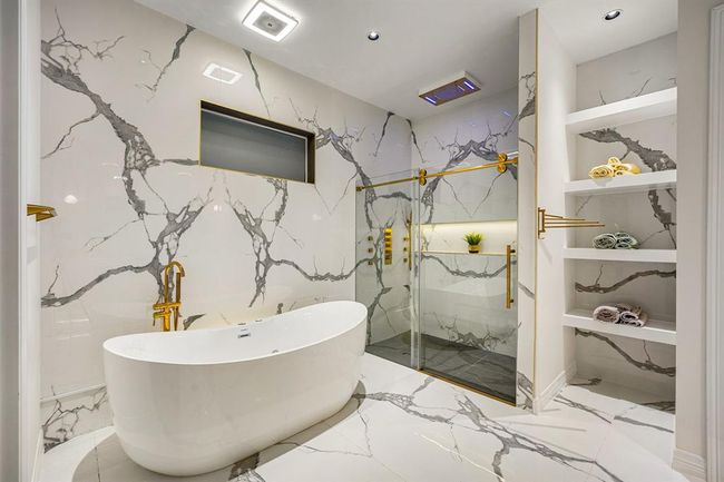 ChatGPT said:Immerse yourself in ultimate luxury with this breathtaking en suite bathroom, showcasing a sculptural freestanding soaking tub, oversized rainfall shower with LED lighting, and striking book-matched marble surfaces throughout. Gold accents and built-in shelving elevate the space, creating a spa-inspired sanctuary designed for pure indulgence. | Image 24