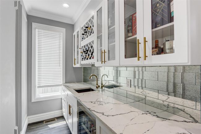 Indoor wet bar with beverage cooler, baseboards, ornamental molding, backsplash, and recessed lighting | Image 10