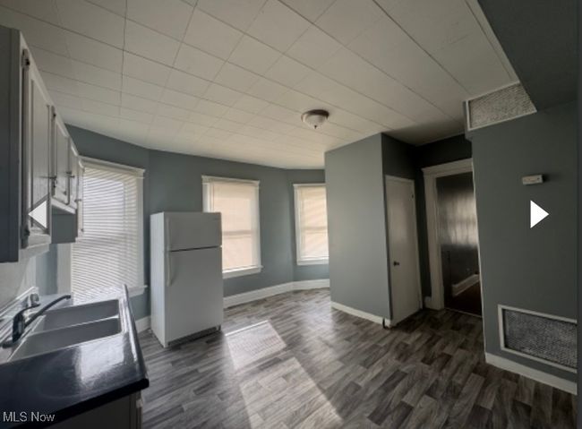 Kitchen with sink, dark wood-type flooring, white cabinets, and white fridge | Image 9